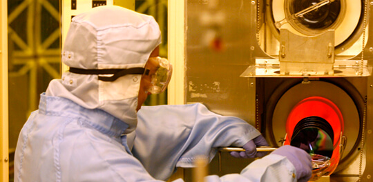 student in lab safety gear working the Microelectronics Laboratory