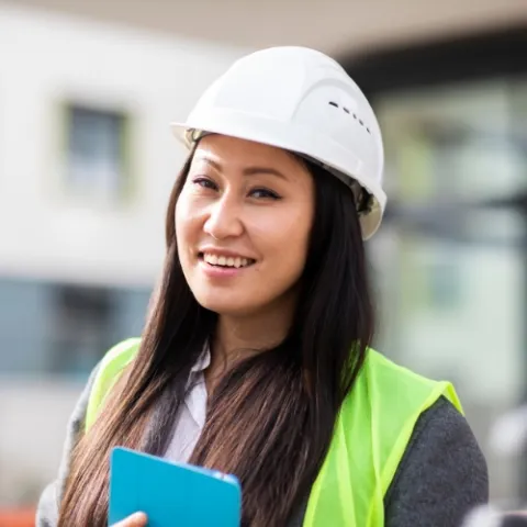 A civil engineering intern in a hardhat at a building jobsite.